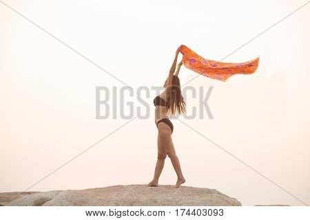 Positive female holding fabric up and expressing gladness while standing stone on isolated.