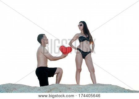 Lovely young adult couple standing on the rocks above tropical sea in isolated.