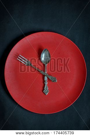 Clock with red plate, spoon and fork  on rusty background