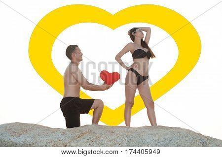Lovely young adult couple standing on the rocks above tropical sea in isolated.