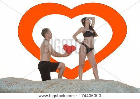 Lovely young adult couple standing on the rocks above tropical sea in isolated.