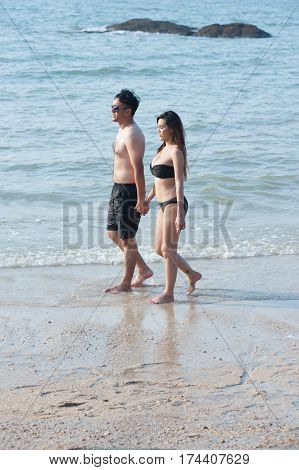 Lovely young adult couple standing on the beach .