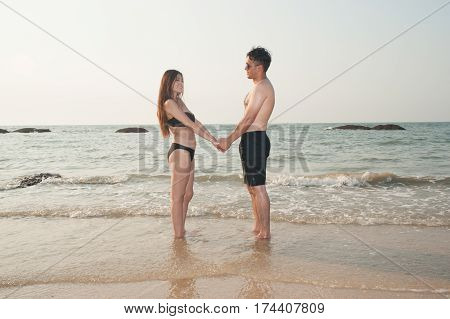 Lovely young adult couple standing on the beach.