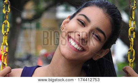 Happy and Smiling Teen Girl Swinging On Swingset