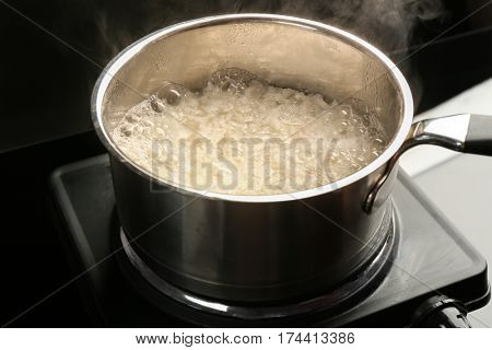 Cooking rice in metal pan on hotplate in kitchen
