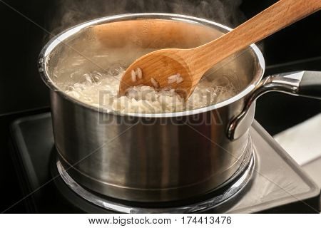 Cooking rice in metal pan on hotplate in kitchen