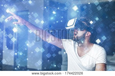 Young man with VR glasses playing virtual reality touching blue squares