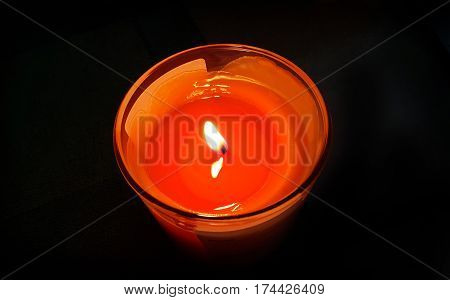 Bright orange burning candle in the dark