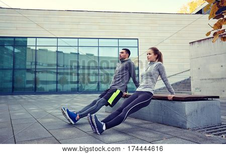 fitness, sport, training, people and lifestyle concept - couple doing triceps dip exercise on bench outdoors