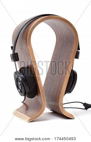 Black Pair of Headphones on a wooden stand Isolated on a White Background