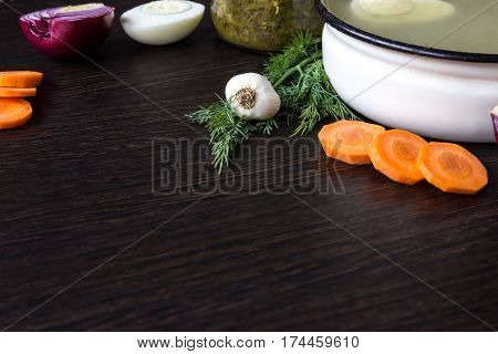 Soup with sorrel vegetables and boiled egg red onion carrots garlic dill on dark wooden table