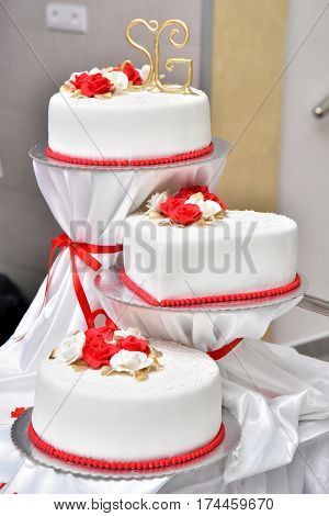 Sweet cakes in the form of red roses decorate the wedding cake with more decorative twigs of white cream. Photographed at a wedding in Novi Sad, Serbia.