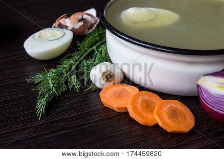 Soup with sorrel vegetables and boiled egg red onion carrots garlic dill on dark wooden table
