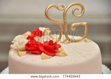 Sweet cakes in the form of red roses decorate the wedding cake with more decorative twigs of white cream. Photographed at a wedding in Novi Sad, Serbia.