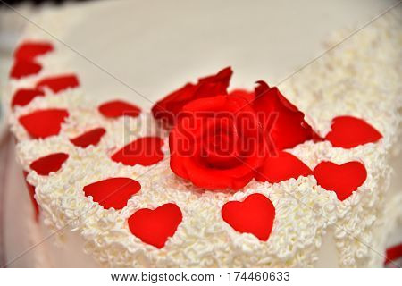 Sweet cakes in the form of red roses decorate the wedding cake with more decorative twigs of white cream. Photographed at a wedding in Novi Sad, Serbia.