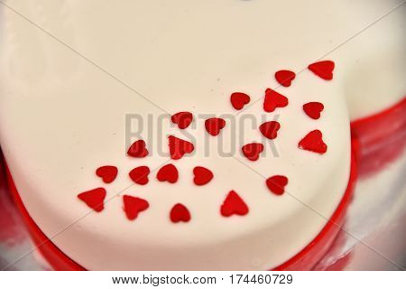Sweet cakes in the form of red roses decorate the wedding cake with more decorative twigs of white cream. Photographed at a wedding in Novi Sad, Serbia.