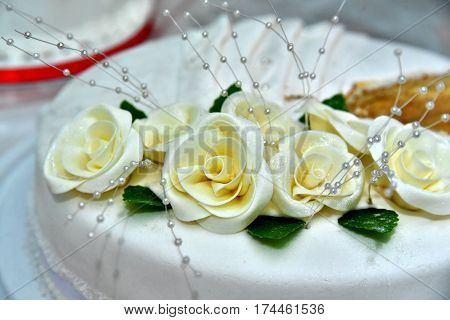 Cute delicious wedding cake decorated with cakes in the shape of red and white roses on the sides decorated with various beads and lines