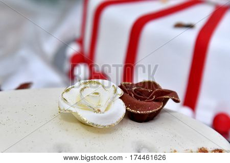 Cute delicious wedding cake decorated with cakes in the shape of red and white roses on the sides decorated with various beads and lines