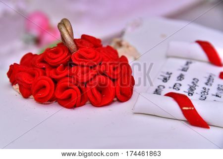 Sweet cakes in the form of red roses decorate the wedding cake with more decorative twigs of white cream. Photographed at a wedding in Novi Sad, Serbia.