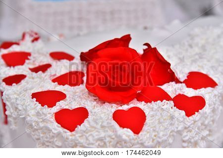 Sweet cakes in the form of red roses decorate the wedding cake with more decorative twigs of white cream. Photographed at a wedding in Novi Sad, Serbia.