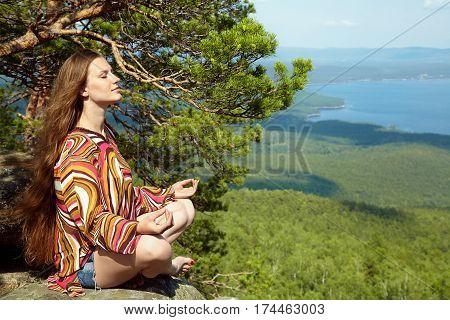 Young beautiful woman meditating at the mountains. relaxation outdoors. nature freedom and inspiration