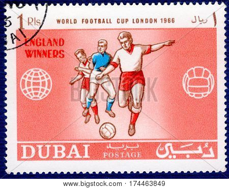 DUBAI - CIRCA 1966: Postage stamp printed in Dubai  with a picture of a football players, with the inscription 