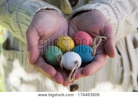 Young woman holding in hands decorative colorful Easter eggs on twine outdoors sun flecks closeup kinfolk style authentic