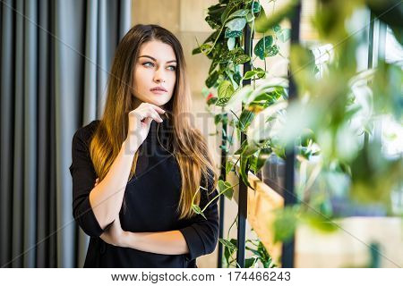 Friendly businesswoman standing with folded arms in a bright office looking at the camera