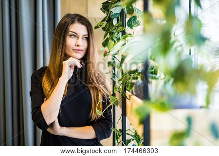 Friendly businesswoman standing with folded arms in a bright office looking at the camera