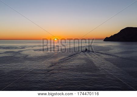 A boat heading into the the sunset in Mediterranean Sea heading off the coast of Vernazza, Cinque Terre, Italy.