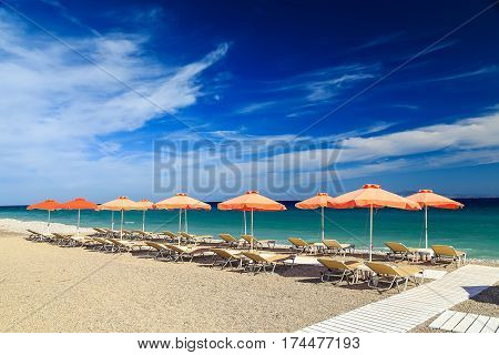 White wooden walkway on beach including umbrellas with deck chairs. Aegean Sea. Greece Rhodes.