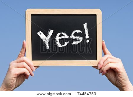 Yes - female hands holding chalkboard with text