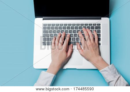 white caucasian female hands typping text on the keyboard on the wonderful blue background