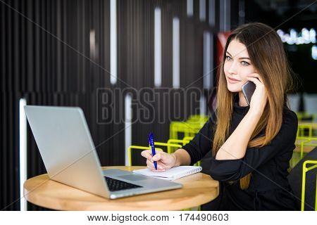 Happy pretty manager talking on mobile phone with client.