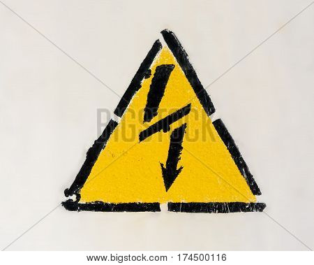 High voltage triangle warning sign mounted on gray metal wall
