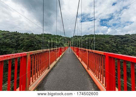 long red bridge and forest with cloudy sky background in Kamikawa Otaki Waterfall Park Kagoshima Kyushu Japan