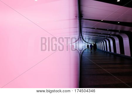 LONDON, UK - MAY 17, 2016: Reflection of people walking through futuristic looking pedestrian tunnel featuring an LED integrated light wall in Granary Square exit from Kings Cross Underground station.