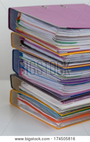 Several multicolored folders with documents stacked in a pile on the table. Close-up