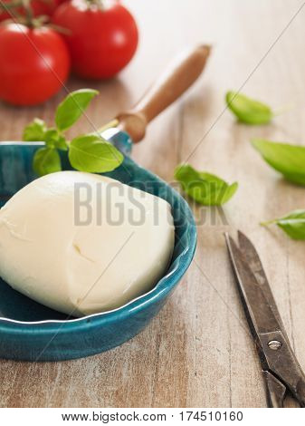 Fresh organic mozzarella with basil and tomatoes in a kitchen selective focus