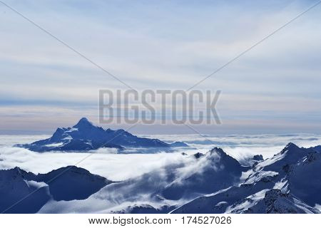 beautiful view of clouds crossing the mountain ridge. awesome mountain landscape with snow-capped peaks, rocks, sky. photo on the theme of winter nature, adventures and travel.