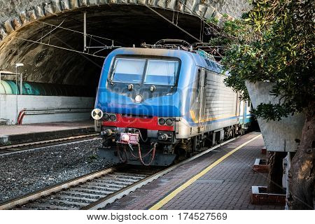Passenger train driving out from tunnel near Riomaggiore town, Cinque Terre, Italy