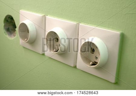 Three white European 220V power socket on green wall in Novi Sad, Serbia