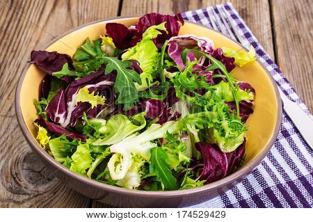 Frise, batavian, radichchio, arugula in a ceramic bowl on a wooden background. Studio Photo