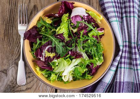 Frise, batavian, radichchio, arugula in a ceramic bowl on a wooden background. Studio Photo