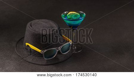 colored drink a combination of blue and green lemon martini glass yellow sunglasses a black hat party set