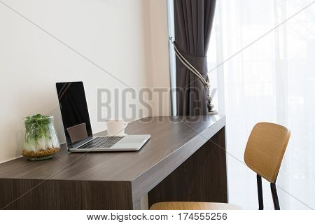 office table with blank screen laptop white coffee cup modern chair and garden plant garden on cement wall background view from front office table concept of business lifestyle.
