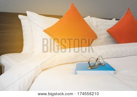 white bed with modern glasses on blue book at bed room.