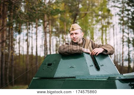 Pribor, Belarus - April 23, 2016: Young Re-enactor Dressed As Russian Soviet Soldier Of World War II Sitting In Armoured Soviet Scout Car BA-64 In Forest.