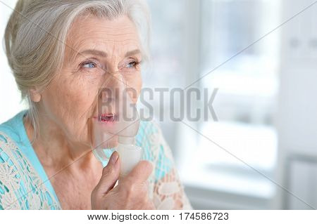 Portrait of a sick elderly woman making inhalation