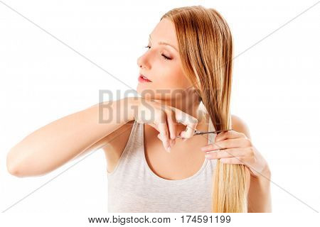 Attractive young woman cutting her long blond hair